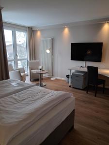 a hotel room with a bed and a desk and a tv at pepb Schulungshotel in Sarstedt
