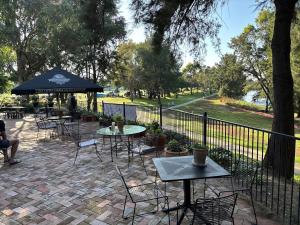a patio with tables and chairs and an umbrella at Bathurst River House B & B in Bathurst