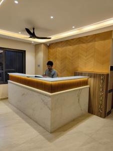 a man sitting at a counter in a lobby at Vyavahar lodge in Udupi