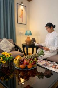 a woman in a room with a table with a bowl of fruit at Yog Niketan Villa in Rishīkesh