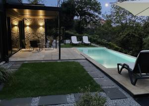 a backyard with a swimming pool with chairs and an umbrella at Chestnut hill - Geres in Ventosa
