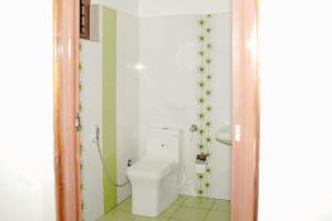 a bathroom with a white toilet in a room at Backwater Home in Kumarakom