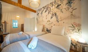 two beds in a room with a wall mural at L'Orée du Bois in La Charmée