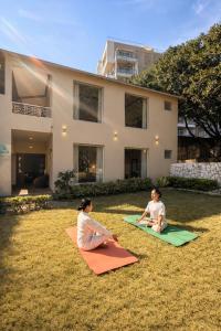 a woman and child sitting on the grass in front of a house at Yog Niketan Villa in Rishīkesh