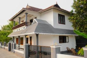 a white house with a black roof at Backwater Home in Kumarakom