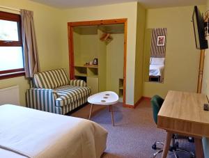 a hotel room with a bed and a chair and a table at Deveron Lodge B&B in Turriff