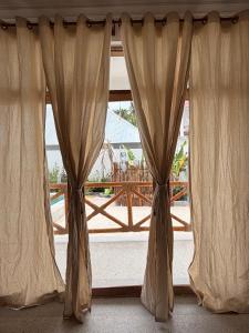 a window with curtains in front of a balcony at Olacoco by Olamanga in Jambiani