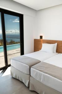 two beds in a bedroom with a view of the ocean at Plethora Luxury Suites in Rodhiá +107 photos