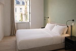 a white bed in a room with a window at Appartements à Oloron in Oloron-Sainte-Marie