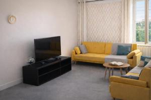 a living room with a yellow couch and a television at Appartements à Oloron in Oloron-Sainte-Marie