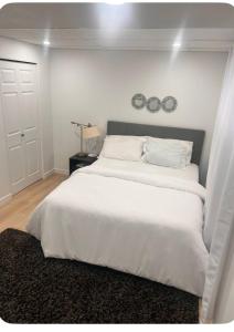 a bedroom with a white bed with two clocks on the wall at Ubbies place in Regina