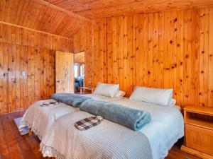 two beds in a room with wooden walls at Bloukrans Off-Grid Cabin in Montagu