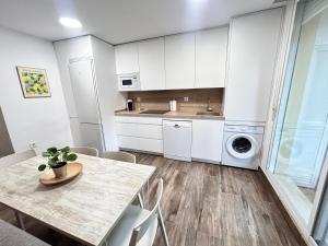 a white kitchen with a table and a washing machine at Dúplex Empul Brisa Marina in Los Caños de Meca +2 photos