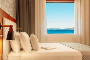 a hotel room with a bed with a window at Zeus Essence Ramada by Wyndham Athens in Mati