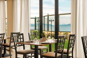 a dining room with a table and chairs and a large window at Zeus Essence Ramada by Wyndham Athens in Mati