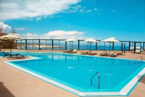 a large swimming pool with chairs and umbrellas at Zeus Essence Ramada by Wyndham Athens in Mati