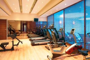a gym with a row of treadmills and elliptical machines at Zeus Essence Ramada by Wyndham Athens in Mati