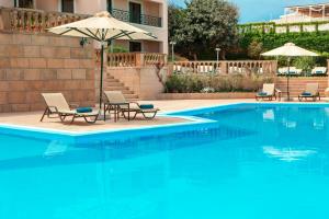 a swimming pool with two chairs and an umbrella at Zeus Essence Ramada by Wyndham Athens in Mati +48 photos