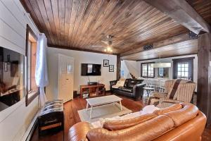 a living room with a leather couch and a table at Spa & Kenogami Lake - Chalet le Rustik in Saguenay