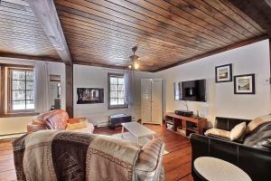 a living room with leather furniture and a wooden ceiling at Spa & Kenogami Lake - Chalet le Rustik in Saguenay +26 photos