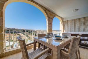 a dining room with a table and chairs and a large window at Gozo Getaway! Heated Jacuzzi & Views in Xagħra