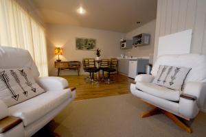 a living room with two white chairs and a table at The Lake Motel in Taupo