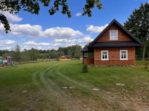 a small house in a field with a playground at Brzozowy Zakątek in Waśki
