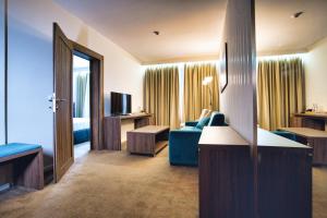 a hotel room with a blue couch and a television at Hotel Nais Nis Autoput in Niš
