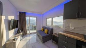 a living room with a couch and a tv and windows at Delfini Girni Apartments in Paralia Katerinis