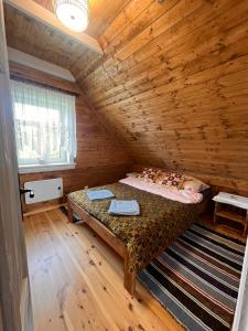 a bedroom with a bed in a wooden room at Brzozowy Zakątek in Waśki