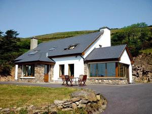 a white house with a black roof with two chairs at 4 Bed in Inch oc-i183 in Anascaul