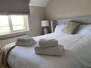 a bedroom with two towels on a bed with a window at 3 Bed in Doonbeg oc-ii15918 in Kilrush