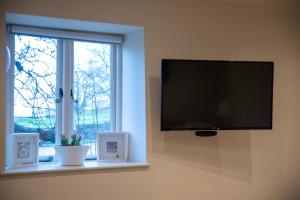 a flat screen tv on a wall next to a window at The End in Langport