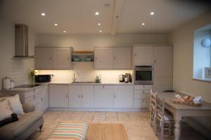 a kitchen with white cabinets and a table and a couch at The End in Langport