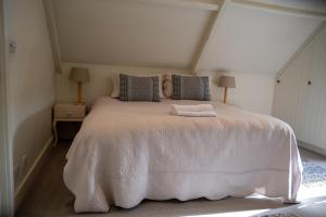 a bedroom with a large white bed with two lamps at The End in Langport