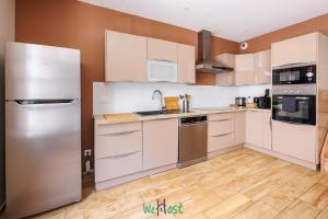 a kitchen with white cabinets and a stainless steel refrigerator at Grand T5 lumineux au cœur de Besançon in Besançon