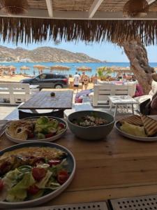 a wooden table with plates of food on a beach at Hotel Delfini in Mylopotas