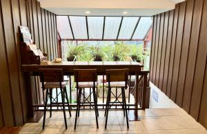 a kitchen with a bar with stools in front of a window at Nuan Nil Secret Courtyard in Chiang Mai