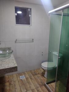 a bathroom with a toilet and a glass shower at Casa para temporada próximo praça do canhão in São Pedro da Aldeia +6 photos