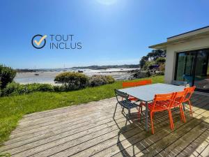 a table and chairs on a deck with a view of the beach at TY KOREJOU - splendide maison avec sauna les pieds dans l'eau in Plouguerneau