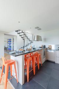 a kitchen with orange chairs and a counter with a table at TY KOREJOU - splendide maison avec sauna les pieds dans l'eau in Plouguerneau