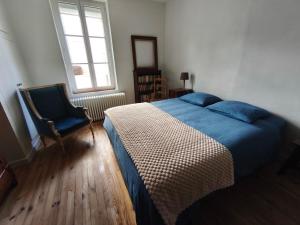a bedroom with a bed and a chair and a window at LES VOLETS BLEUS in Metz