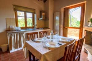 a dining room with a table with chairs and a kitchen at Agriturismo Podere Santo Stefano in Cinigiano