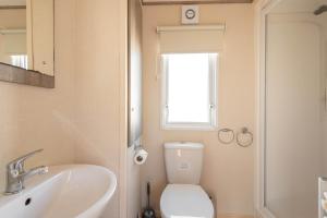 a bathroom with a toilet and a sink and a window at Peaceful Spot at Seton Sands 3-Bed Caravan near Edinburgh in Port Seton