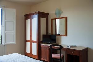 1 dormitorio con escritorio, TV y espejo en Alle Querce Hotel Ristorante, en Castelbuono