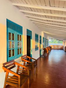 a row of wooden chairs and tables in a room at Reef Inn by COOP in Hikkaduwa +1 photo