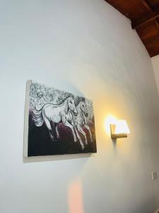 a painting of horses on a wall next to a lamp at Reef Inn by COOP in Hikkaduwa