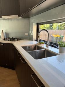 a kitchen with a stainless steel sink and a window at Monash Ensuite room with shared kitchen & laundry in Oakleigh East