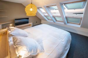 a bedroom with a large white bed and a tv at ILE WRACH - Duplex de luxe avec magnifique vue mer in Landéda