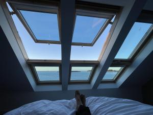 a person laying on a bed in a room with four windows at ILE WRACH - Duplex de luxe avec magnifique vue mer in Landéda